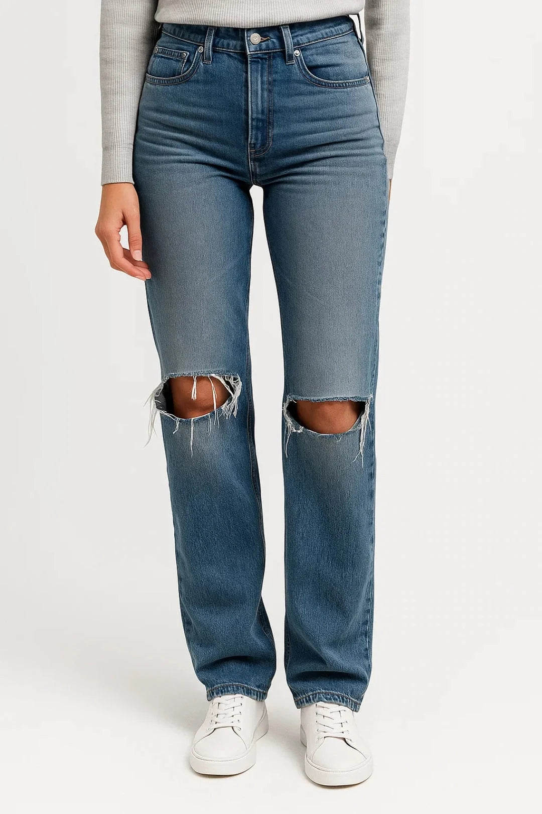 Close-up view of women's straight leg jeans showing distressed ripped knees and classic denim construction