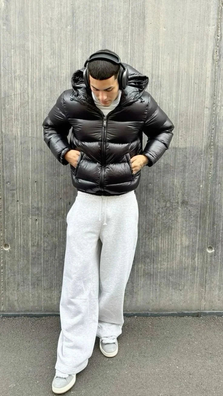 Men's puffer jacket in black with quilted design and hood, styled with grey joggers
