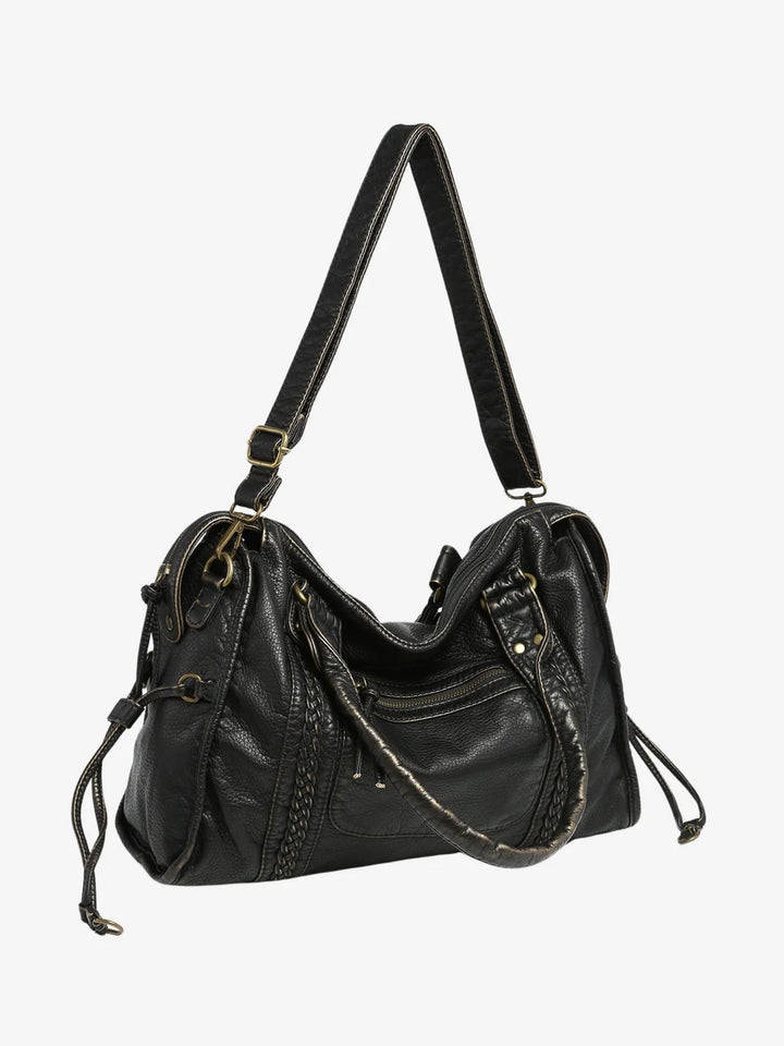 Side view of gathered tie detail with tassel ends on textured shoulder bag