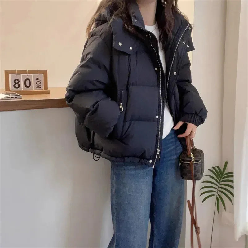 Women's hooded puffer jacket in black with high neck and quilted design worn with jeans
