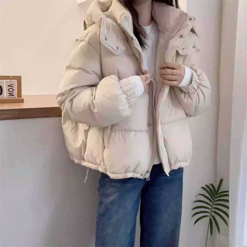 Women's black hooded puffer jacket worn open over white tee and denim jeans