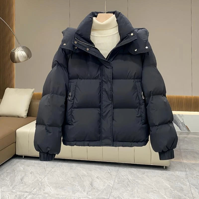 Close-up view of women's black hooded puffer jacket showing zip front and snap-button closure