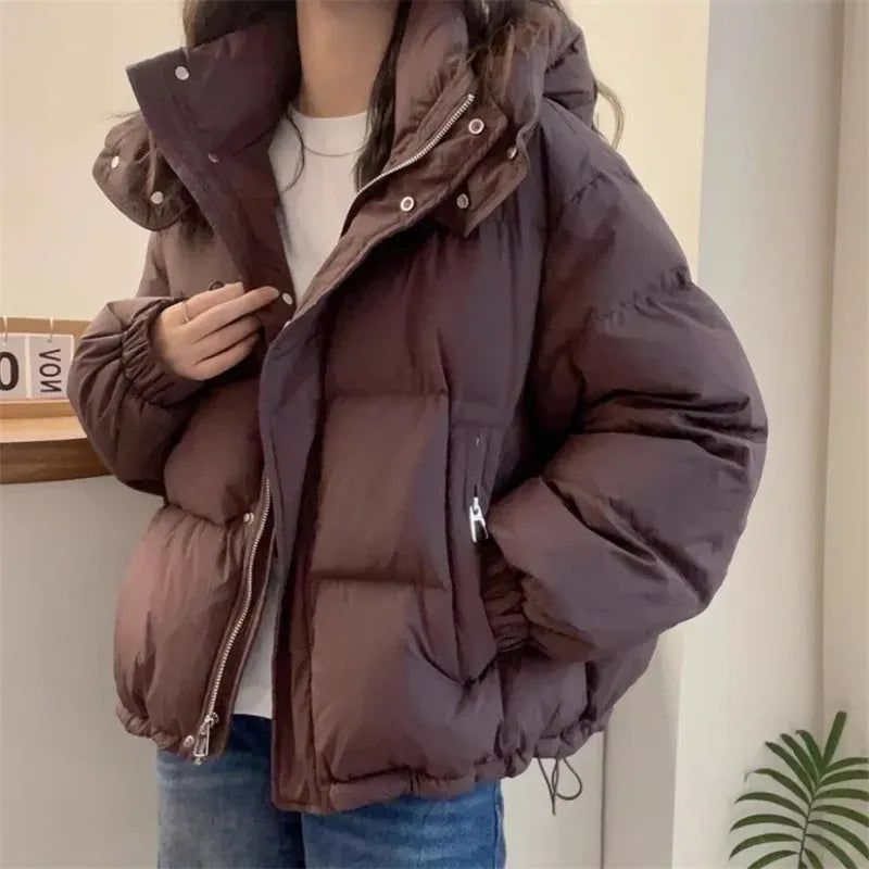 Women's hooded puffer jacket styled with casual trousers and crossbody bag