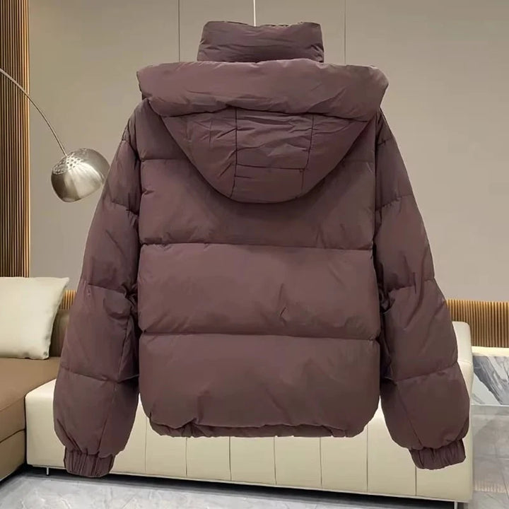 Women's hooded puffer jacket in black displayed on model showing dropped shoulder design