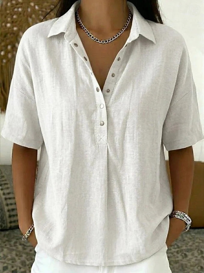 Full-length view of women's relaxed collar shirt paired with white trousers and accessories