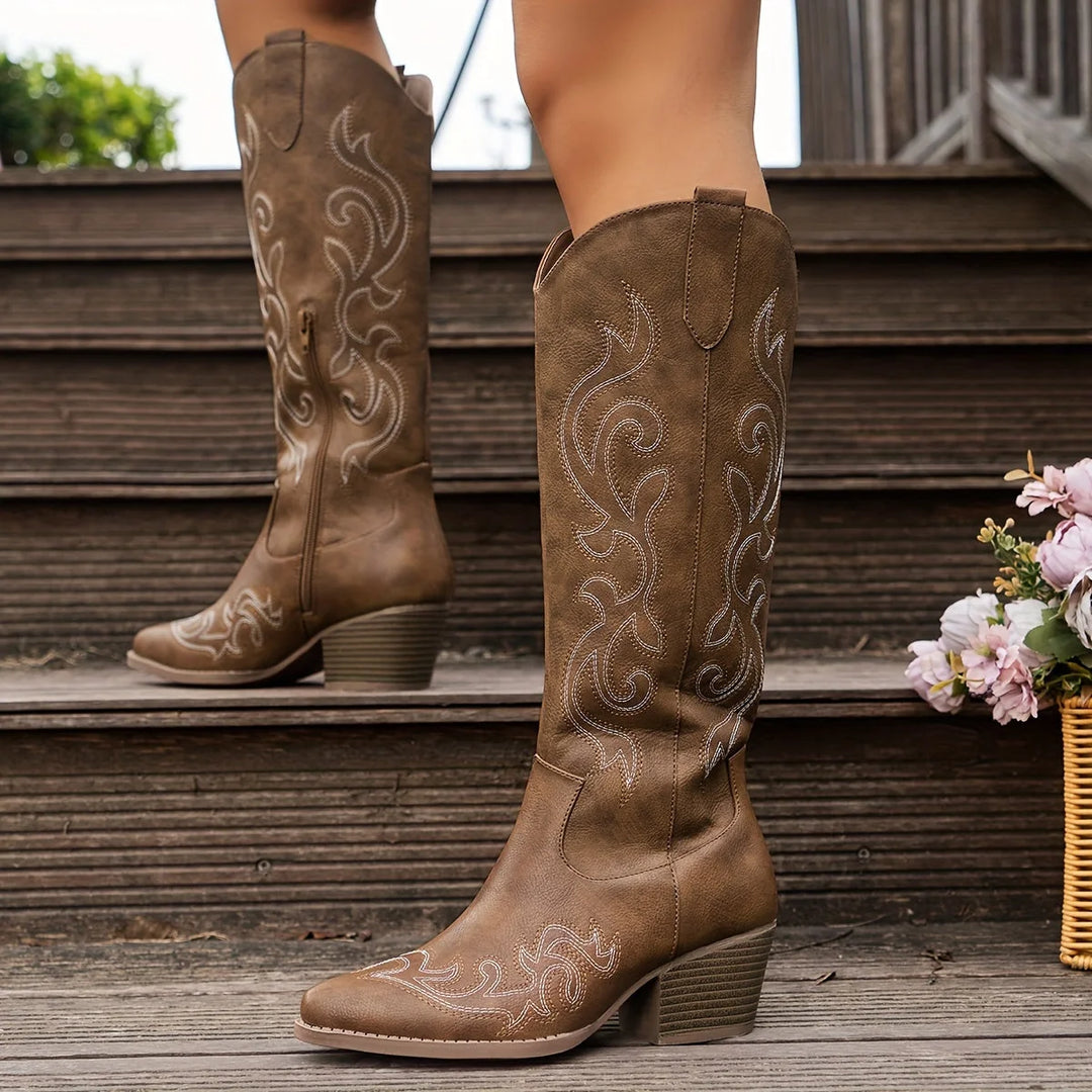 Close-up of embroidered western stitching on white knee-high cowboy boots with pointed toe