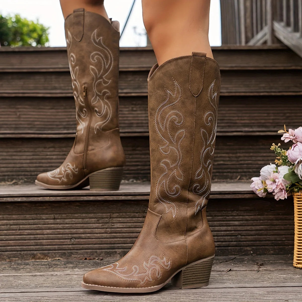Close-up of embroidered western stitching on white knee-high cowboy boots with pointed toe