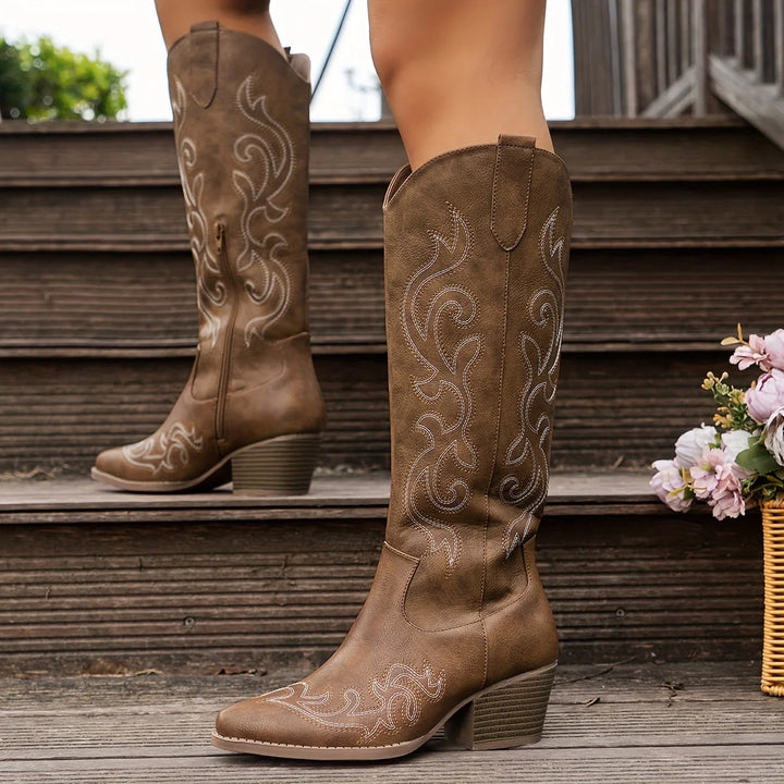 Close-up of embroidered western stitching on white knee-high cowboy boots with pointed toe