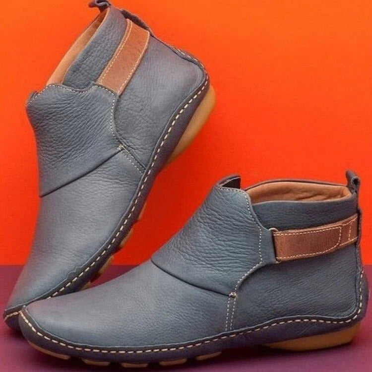 Pair of burgundy ankle boots with elasticated gussets and tan-toned heel tab on purple background