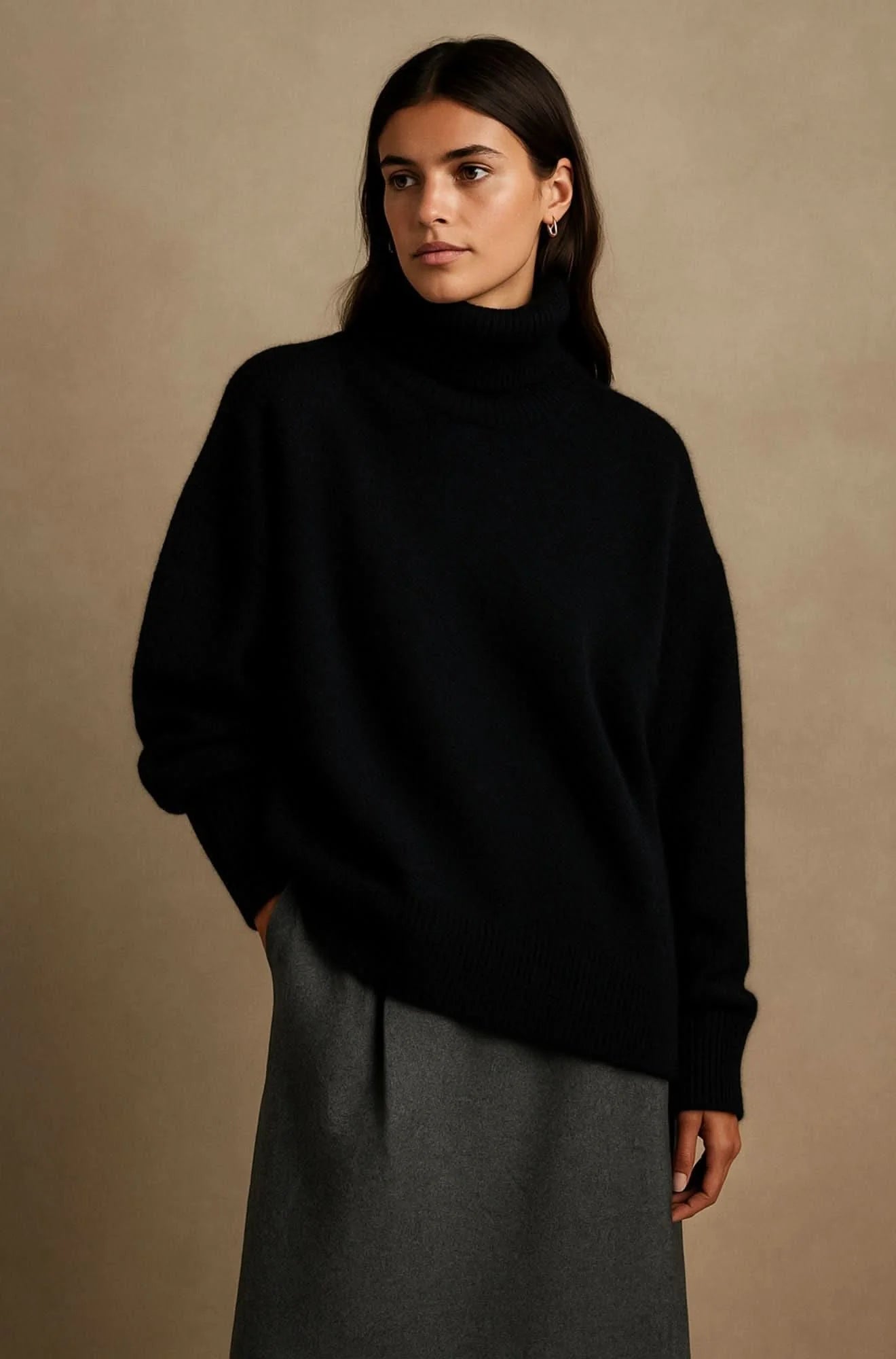 Woman wearing oversized black turtleneck jumper with relaxed fit and ribbed cuffs styled with grey skirt