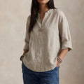 Relaxed linen blouse with V-neckline and single button detail in neutral beige tone