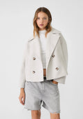 Women's double breasted blazer in light beige with wide lapels and cropped length styled over white knitwear