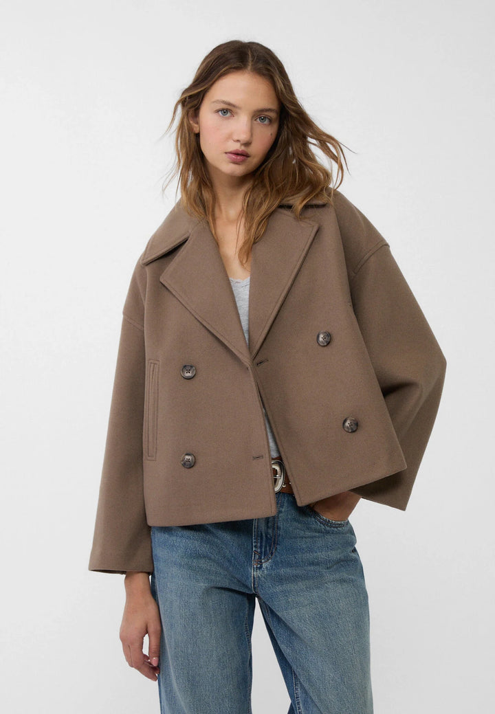 Side profile of cropped blazer highlighting relaxed fit and angled welt pockets at hips