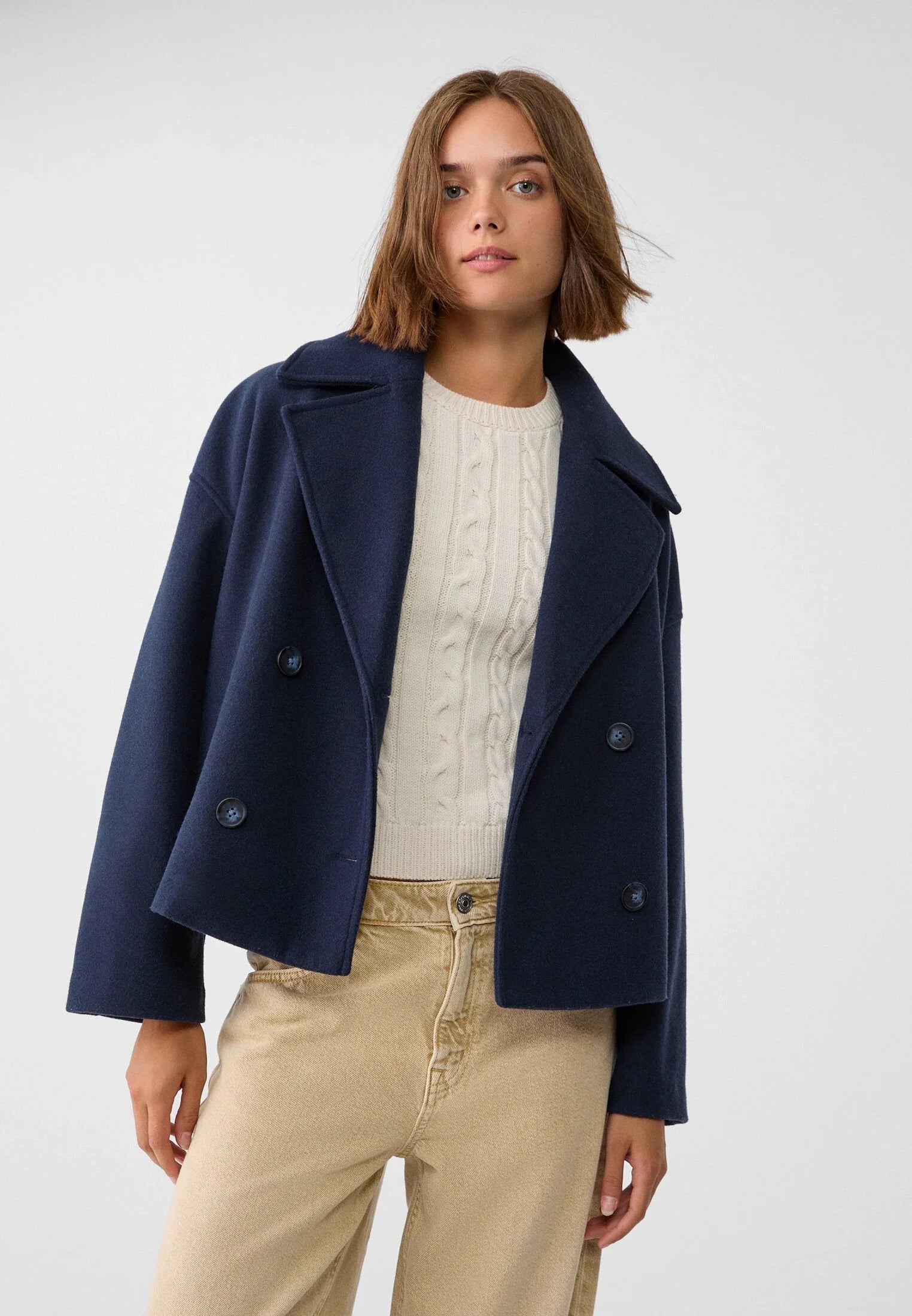 Detail of double breasted button closure and wide notch lapels on structured blazer