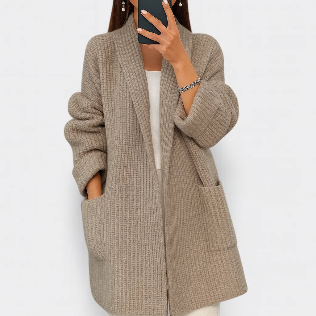 Woman wearing taupe oversized knit cardigan with ribbed texture and open front styling over white top