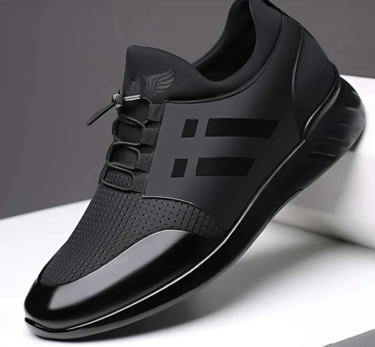 Close-up view of men's black trainers showing smooth upper and flexible lace-up design