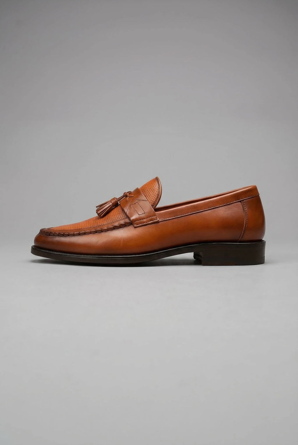 Men's black tassel loafers displayed from three-quarter angle highlighting refined finish
