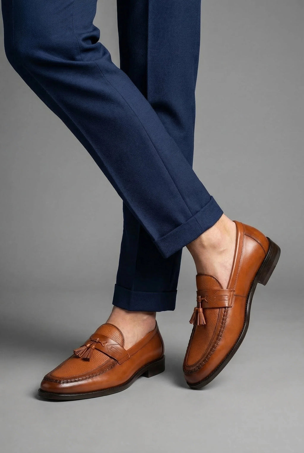 Pair of men's tassel loafers positioned to show woven vamp and formal styling details