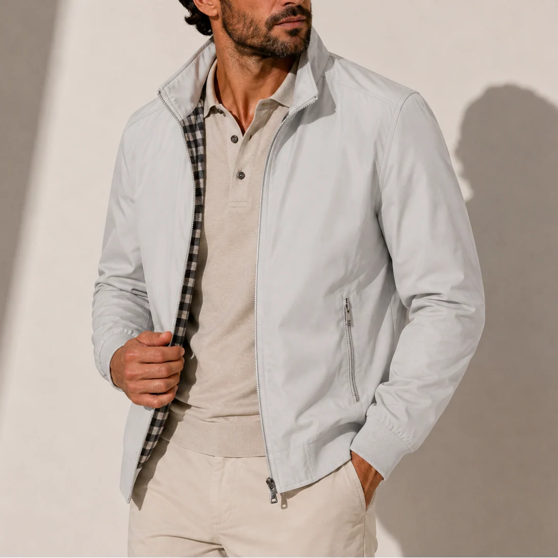 Men's bomber jacket in light grey with stand collar and full zip closure worn over beige polo
