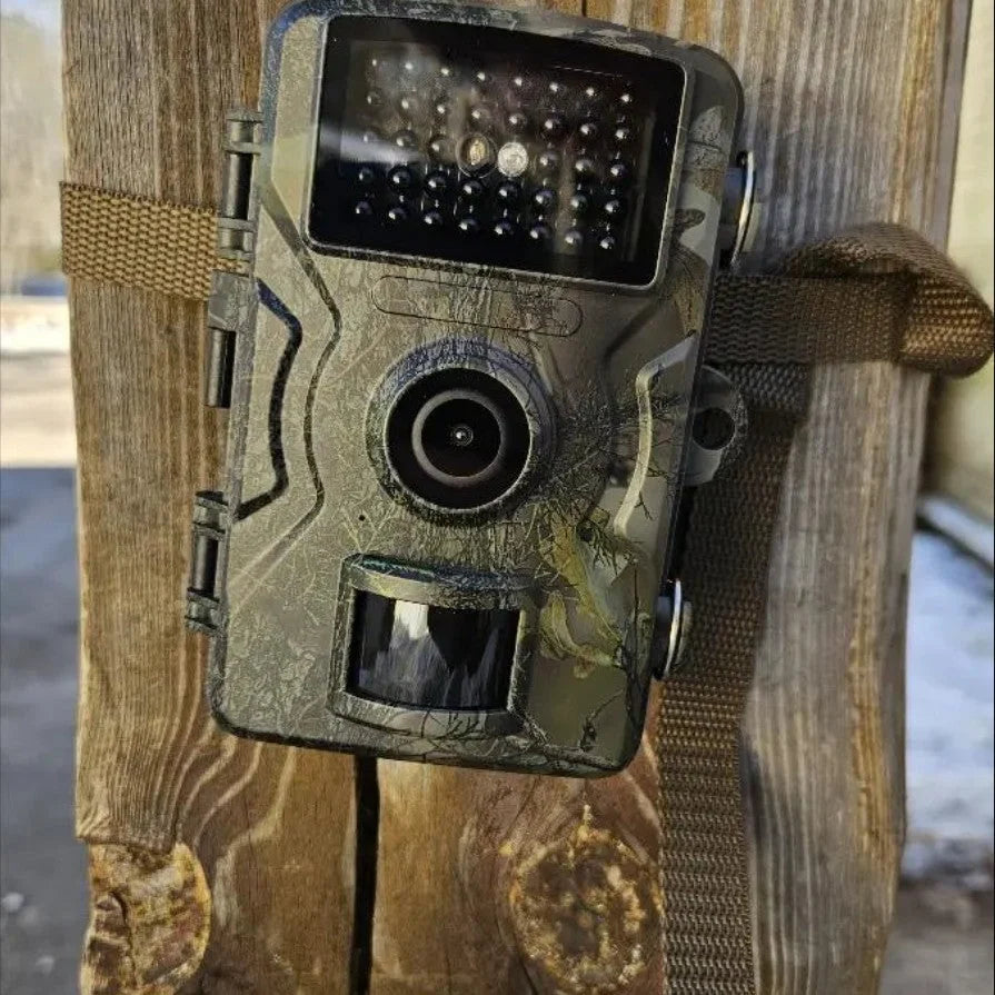 Trail camera with night vision mounted on wooden post showing infrared LED array and camouflage housing