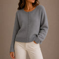 Women's knit cardigan in grey with round neckline and button-up front styled with cream trousers