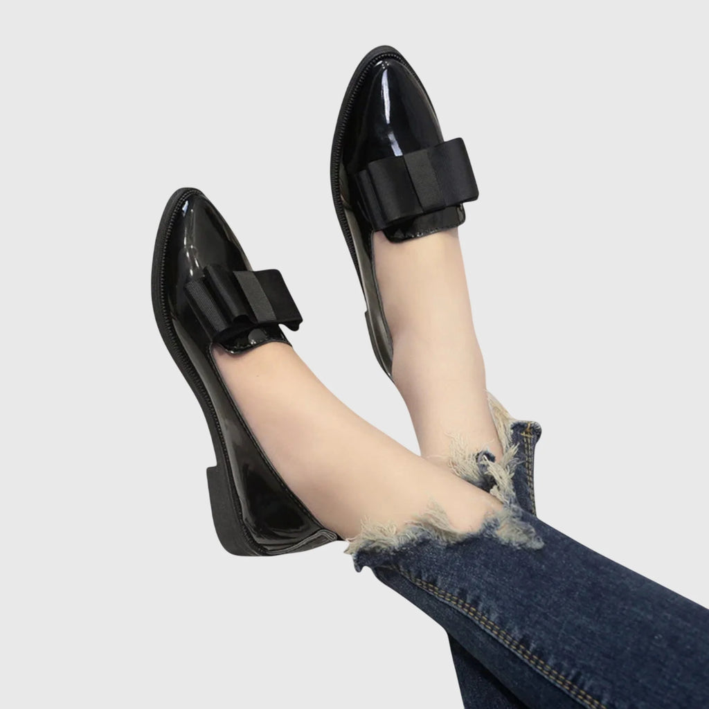Women's patent loafers styled with black trousers showing flat heel and refined silhouette