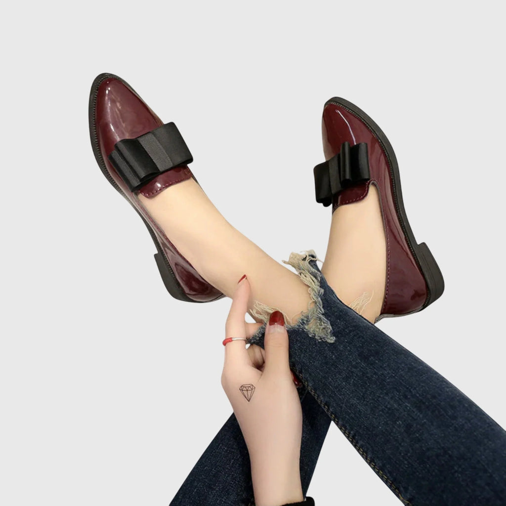 Detailed view of women's loafers showing patent texture and bow construction at vamp
