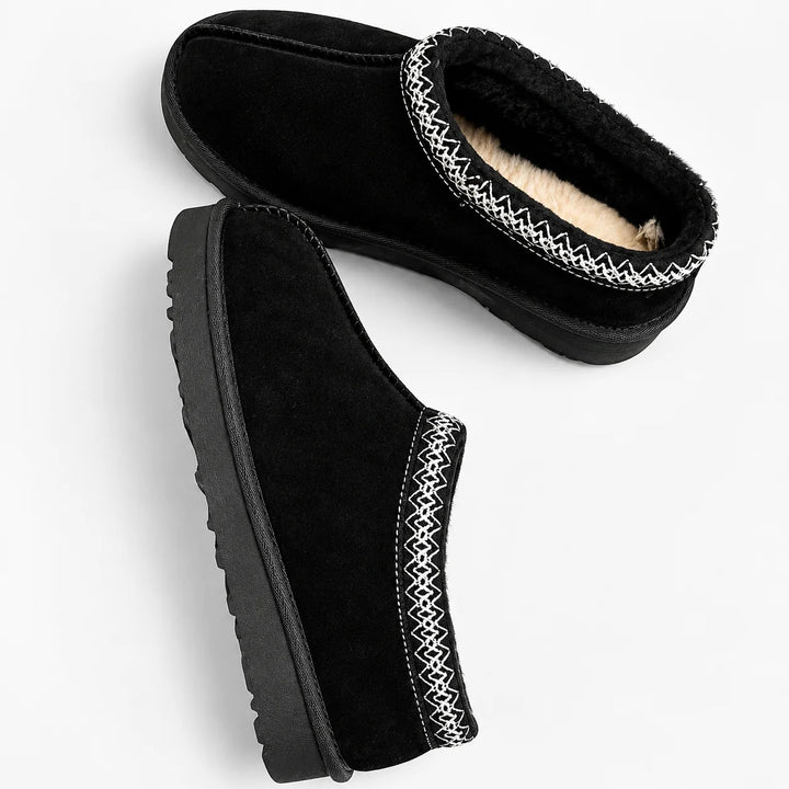 Detail of women's fleece lined slippers with decorative trim and slip-on construction