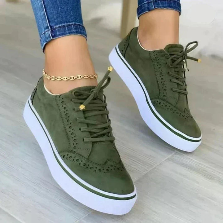 Close-up of women's platform trainers showing perforated brogue design and thick white sole