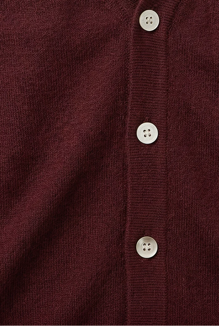 Side view of men's V-neck cardigan displaying ribbed cuffs and structured hem