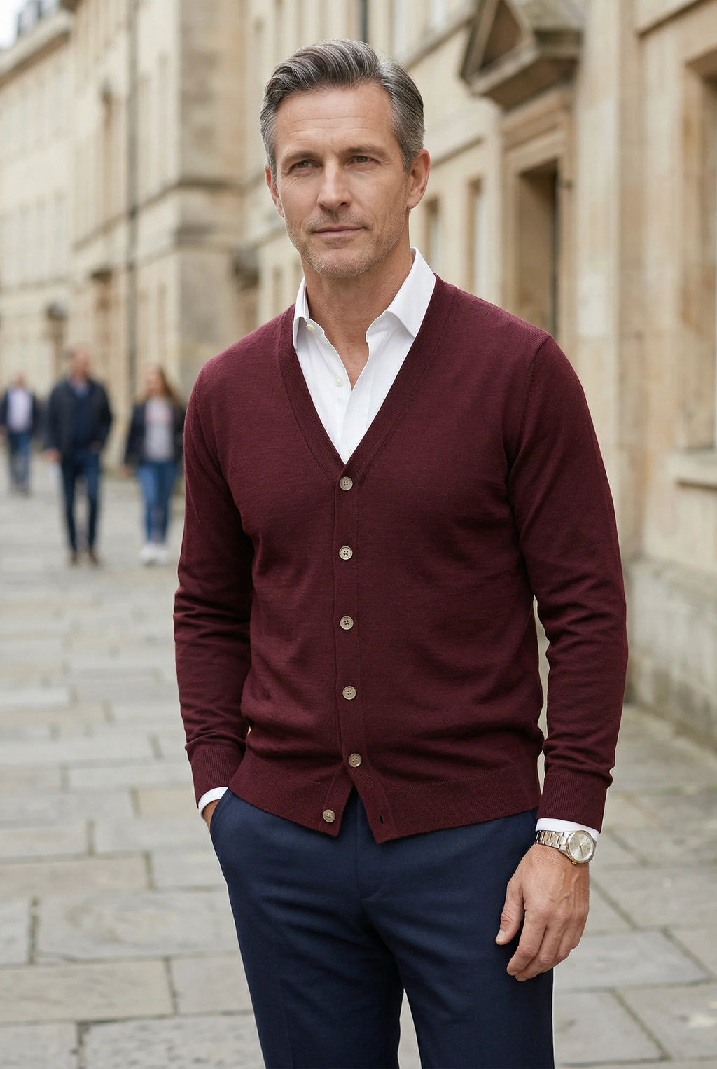 Men's burgundy cardigan layered over formal shirt with tailored trousers