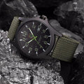 Side profile of black military watch with adjustable canvas strap and protective crown
