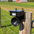 Ultrasonic bird deterrent mounted on wooden fence post in garden setting with motion sensor and solar panel