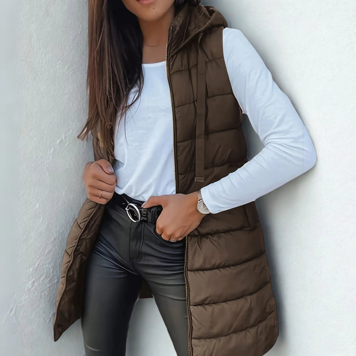 Full-length view of black hooded puffer gilet showing versatile sleeveless design for transitional weather