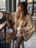Woman wearing beige oversized cable knit jumper with dropped shoulders and chunky ribbed hem