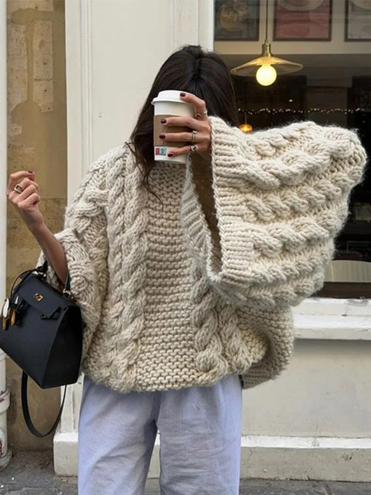 Side view of beige cable knit jumper with relaxed fit and ribbed crew neckline