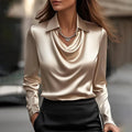 Women's satin blouse with draped neckline and tailored collar in champagne beige worn with black trousers