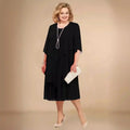 Layered midi dress in black with flowing overlay and round neckline for wedding guest attire