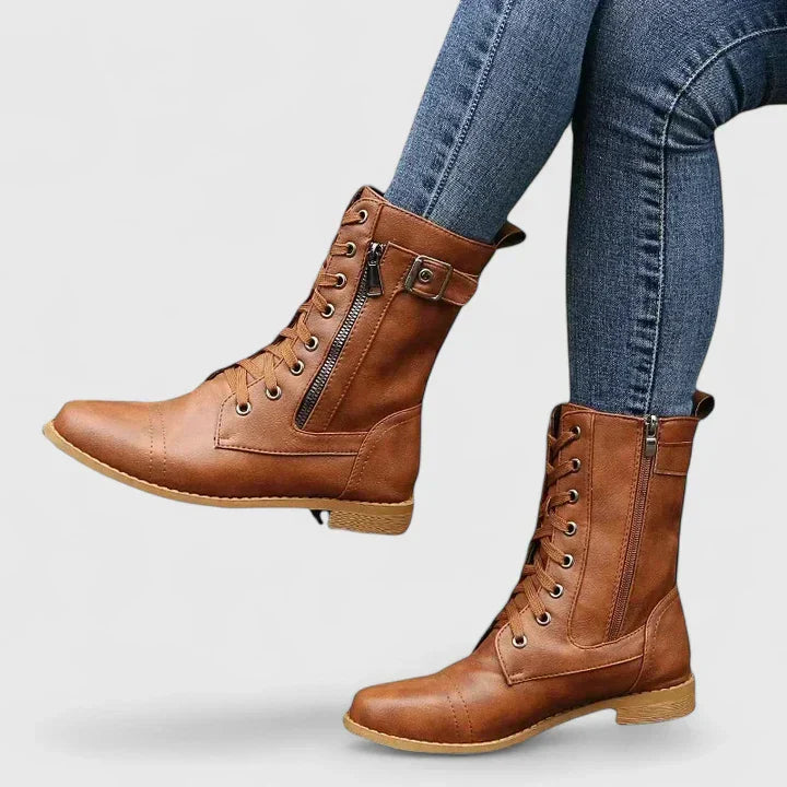 Ankle-height combat boots with decorative buckle strap and tonal stitching detail