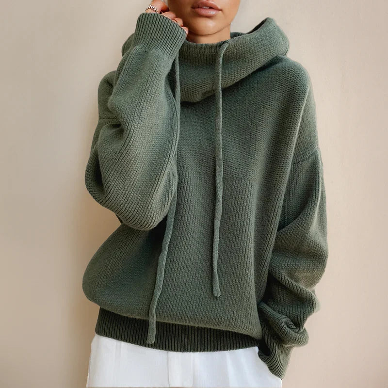 Side profile of women's hooded knit jumper paired with white trousers for casual styling