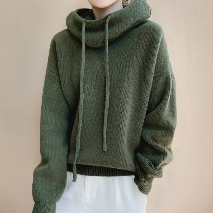 Detail shot of women's hooded knit jumper featuring adjustable drawstring hood and relaxed shoulders