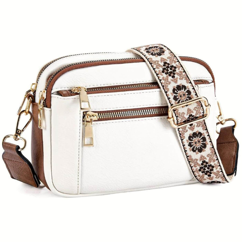 White crossbody bag with embroidered floral strap and gold hardware featuring three zip compartments