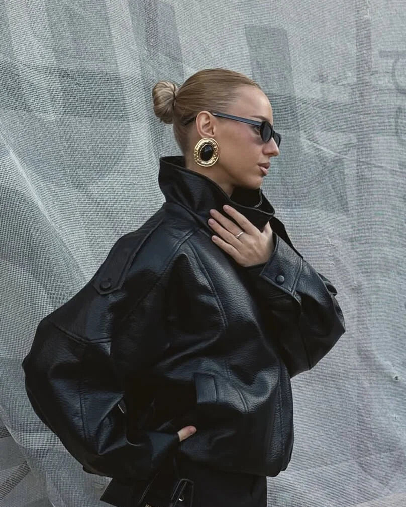 Detail of high neck collar and snap button closure on women's faux leather jacket