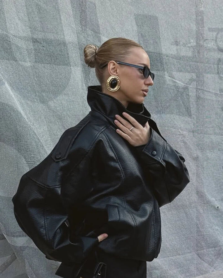 Detail of high neck collar and snap button closure on women's faux leather jacket
