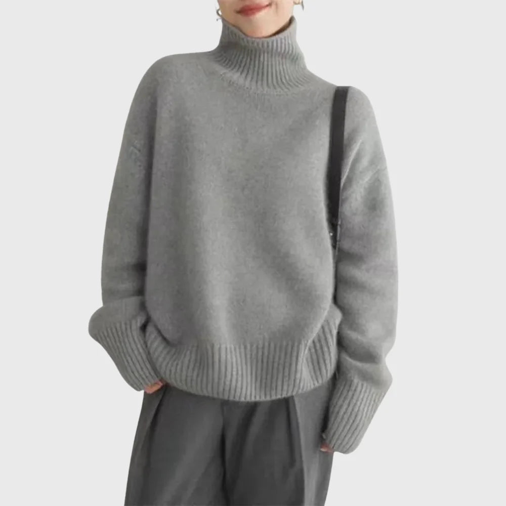 Women's beige turtleneck jumper styled casually showing draped silhouette and ribbed hem finish
