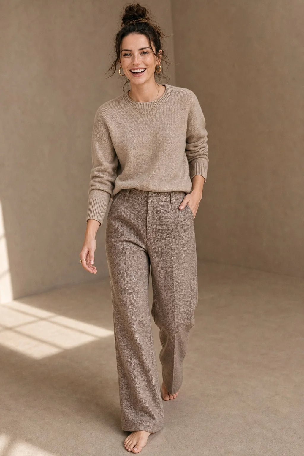 Woman wearing camel wool trousers with herringbone texture and high-waist straight-leg fit paired with a neutral jumper