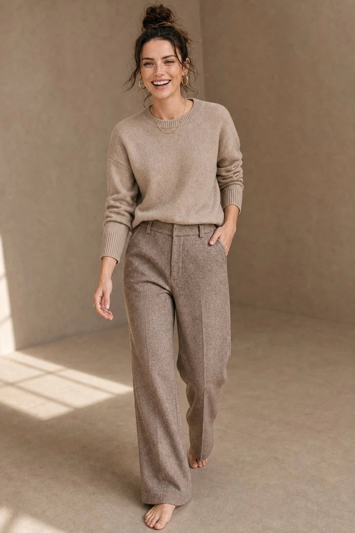 Woman wearing camel wool trousers with herringbone texture and high-waist straight-leg fit paired with a neutral jumper