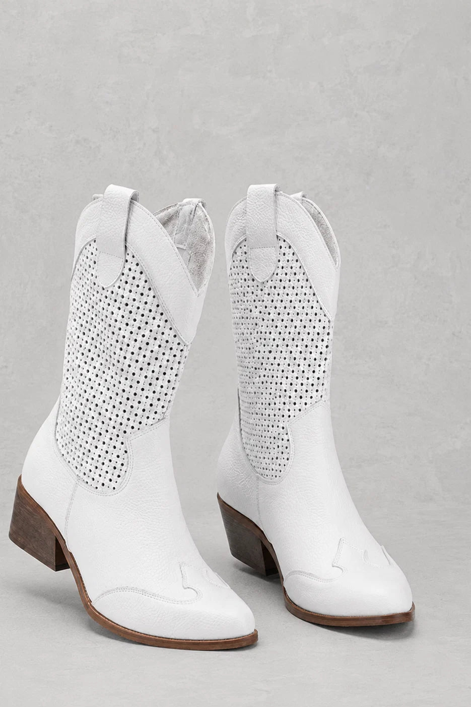 Women's cowboy boots in white with perforated detailing and block heel on neutral background