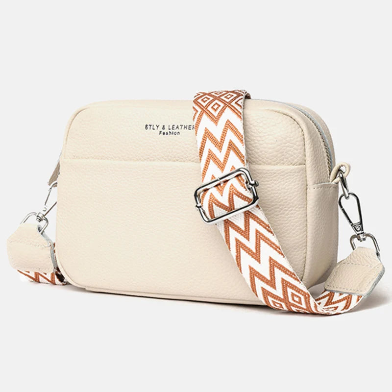 Women's crossbody bag with dual zip pulls and wide geometric strap in tonal shades