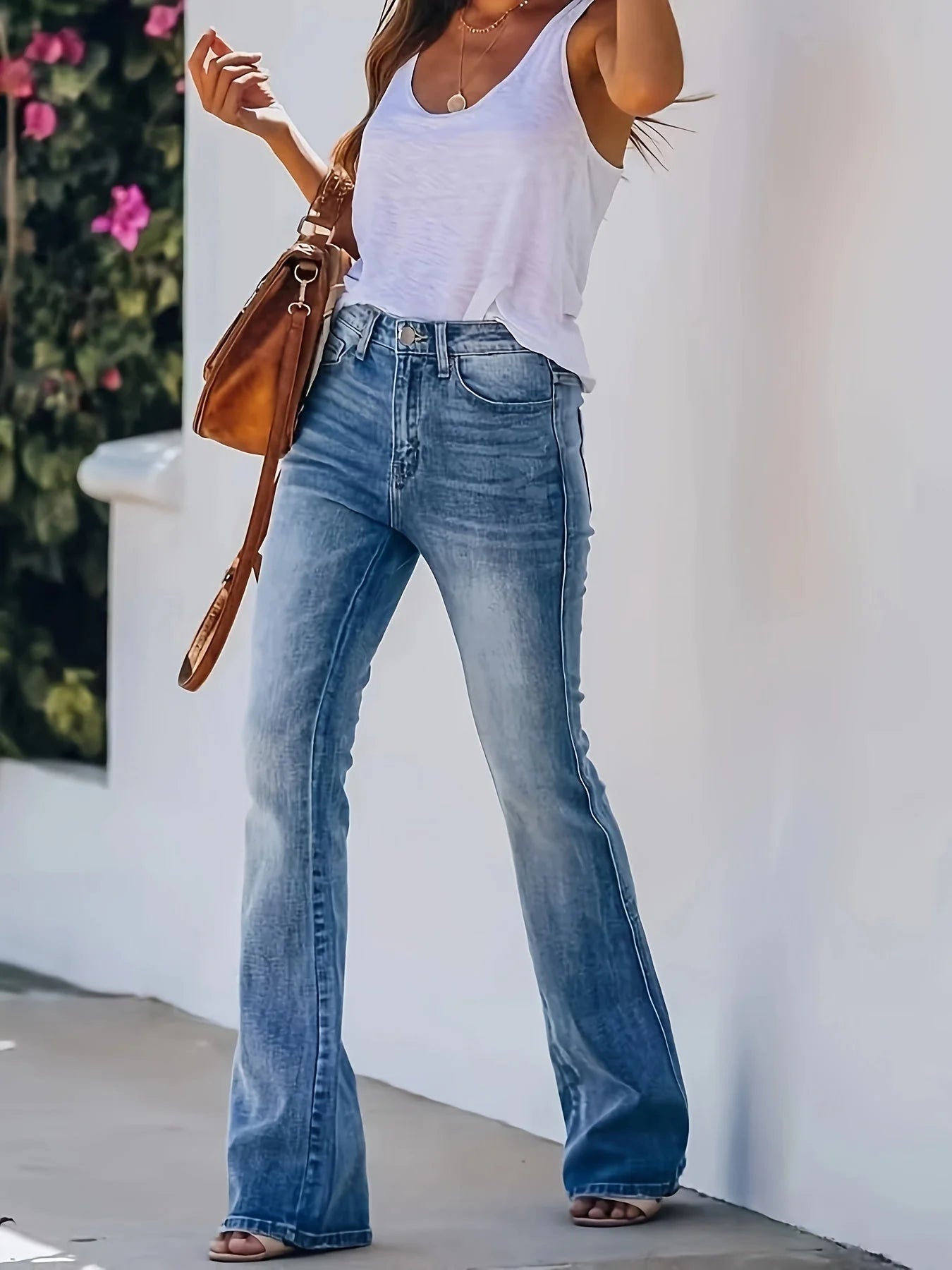 Full-length view of women's flare jeans styled with casual top and heeled sandals